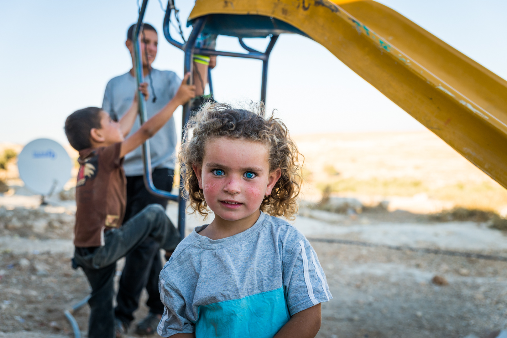A Palestinian girl stands in front of a slide in Susiya.