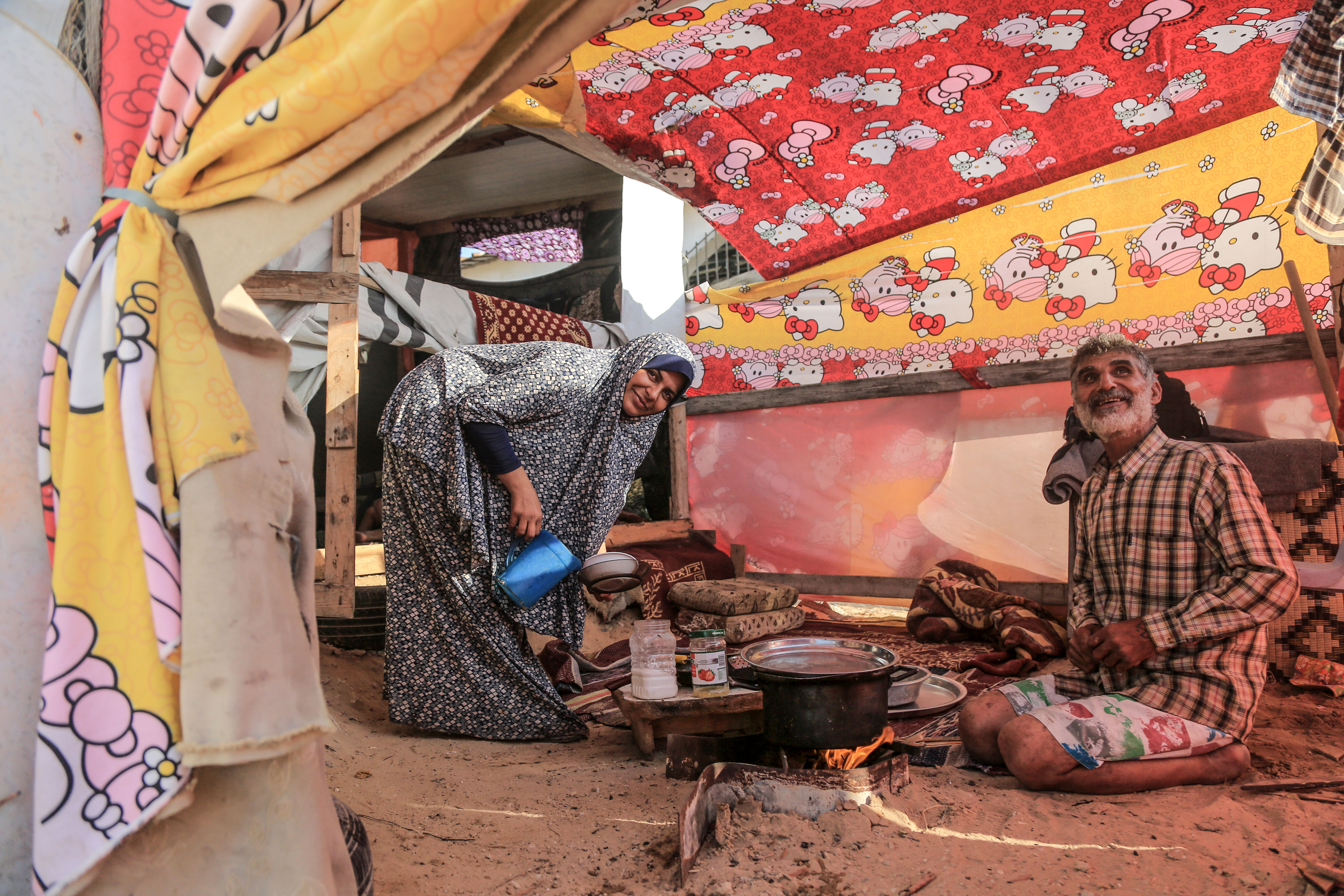 Umm Ahmad prepares iftar inside her tent. She cooks on scraps of wood that her husband Hani collects from the streets of Gaza. The al-Lahham family has been living in this makeshift tent for three years.