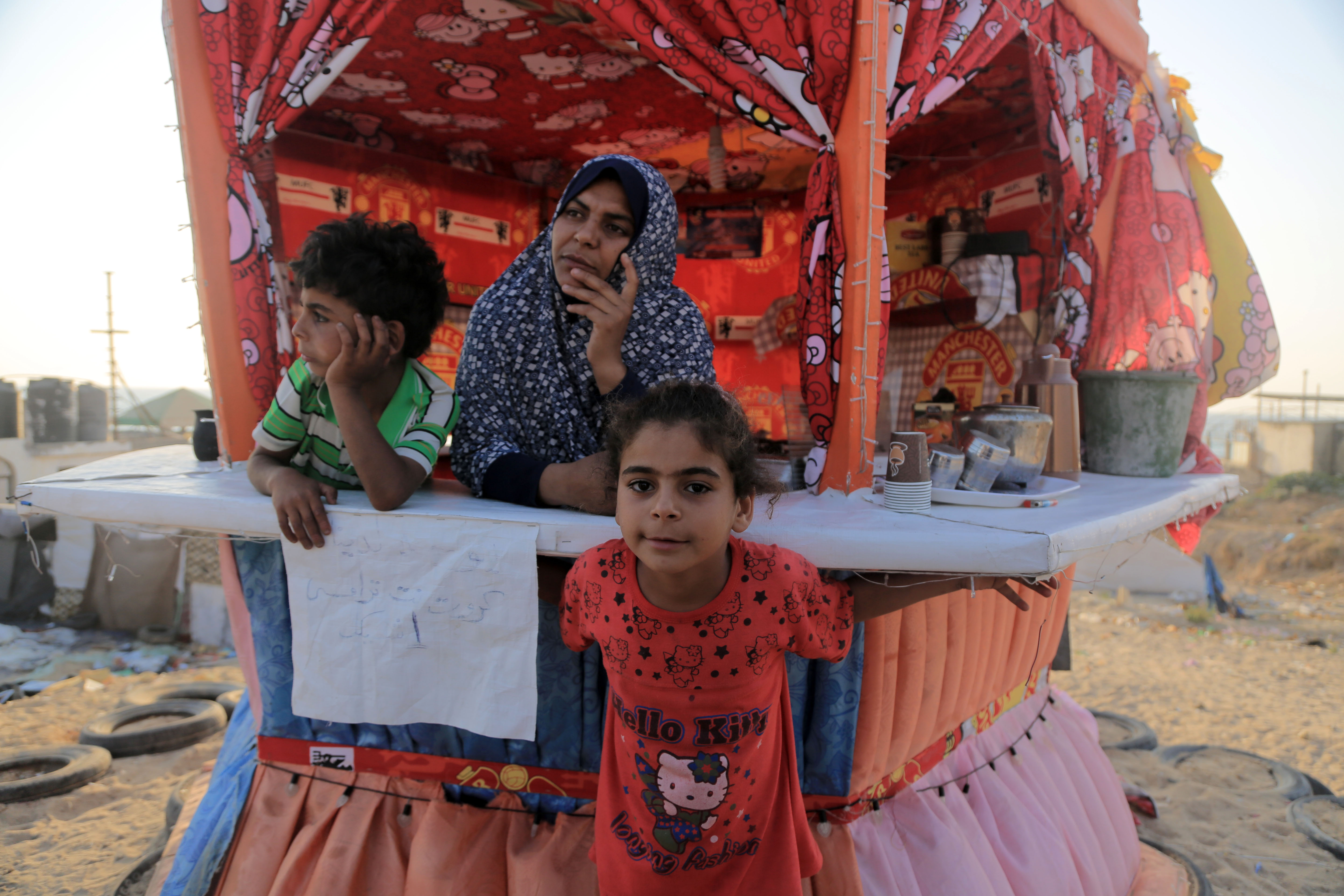  Umm Ahmad, Malak and Ahmad watch potential future customers walk past their tea and coffee shack. It is almost time to prepare their own iftar meal.