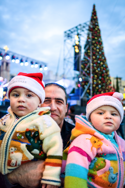 Awad Kassabri, from Nazareth with his 1 year-old twins, Jule and Jullene. They are in front of the Christmas Tree before the lighting celebration outside The Church of the Annunciation in Nazareth.