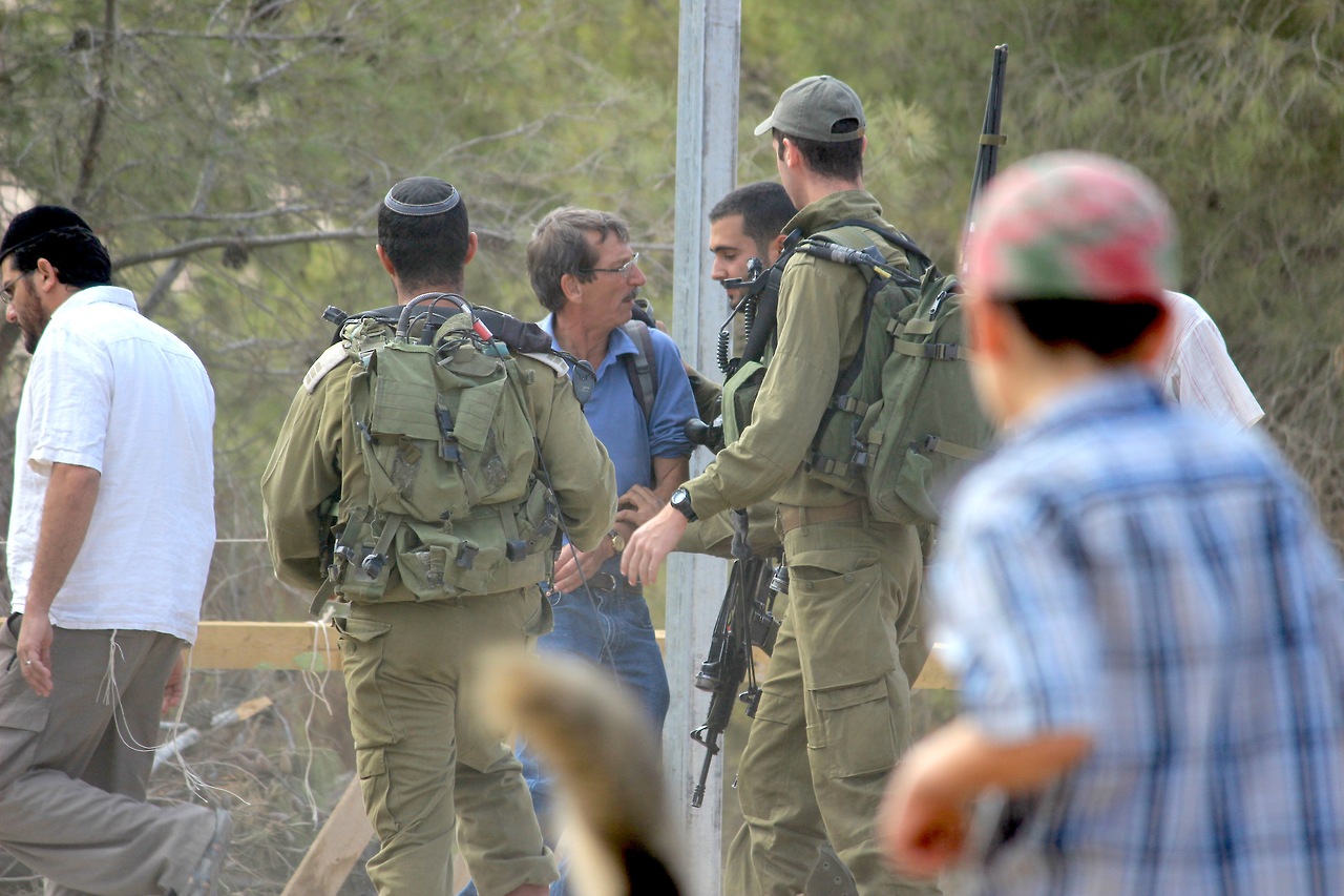 Soldiers shove an Israeli activist, preventing him from monitoring the growth of the outpost.